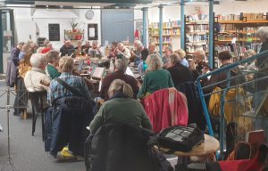 Gruppenphoto Menschen sitzen um eine Tischgruppe und spielen Ukulele